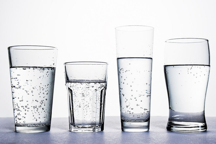Four adjacent carbonated water glasses on white countertop