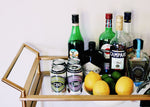 Cocktail ingredients on barcart with cans of Sparkling CBD Ginger Ale and Black Cherry soda