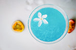 Blue slushie with white flower garnish on white table