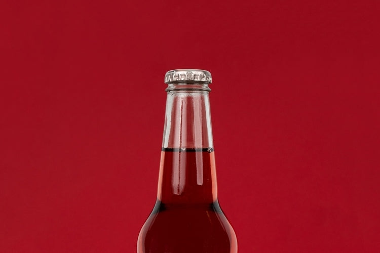 Top of glass soda bottle of cherry soda against red background