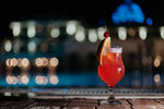 Blended daiquiri cocktail in glass with fruit garnish on ground beside outdoor pool