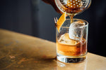 Old Fashioned cocktail poured through strainer into rocks glass