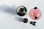 Cocktail shaker, jigger and berries beside glass with iced beverage on white countertop