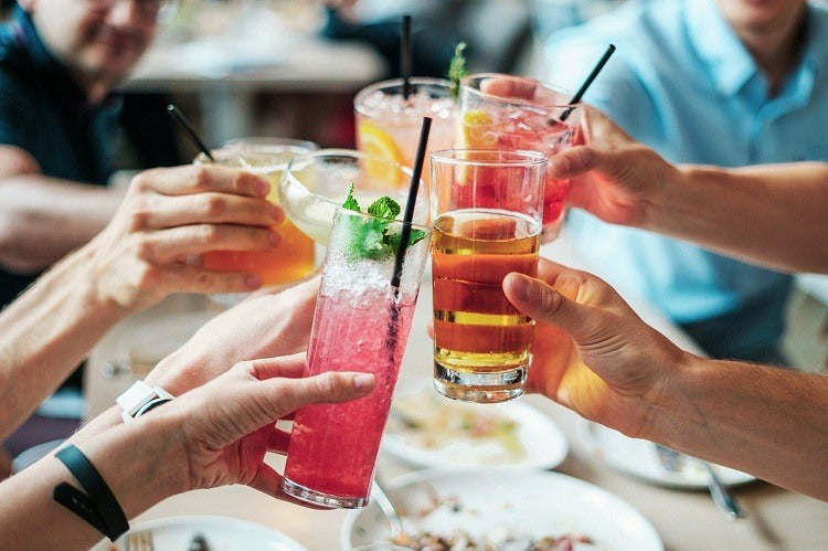 Friends toasting raised drink glasses at dinner table