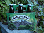 Six pack labelled 'hemp ale' on outdoor deck in dim lighting