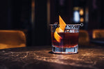 Old fashioned cocktail in glass on granite countertop in dark bar
