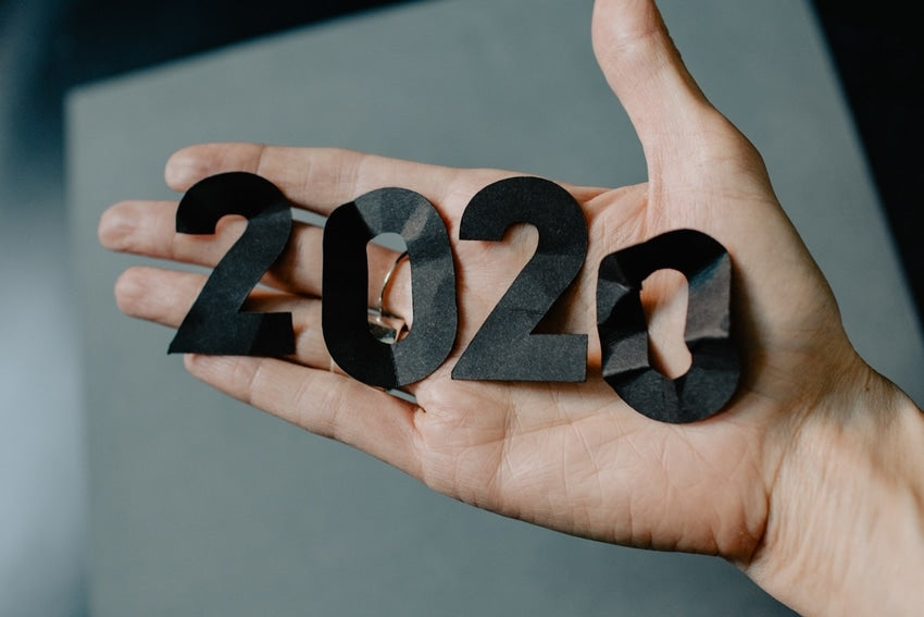 Outstretched hand holding '2020' in crumpled, black paper cutout numbers