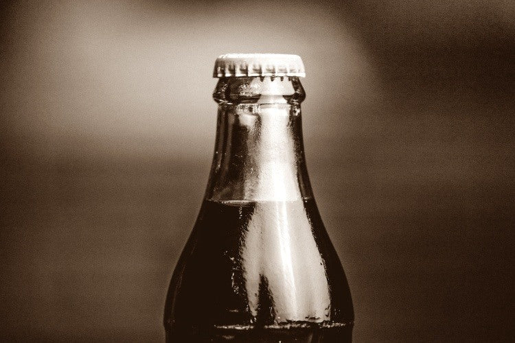 Top of glass soda bottle with white lid in close-up sepia photograph