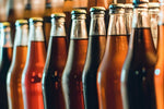 Glass soda bottles in assorted flavors lining photographed close-up on shelf