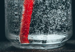 Sparkling water in glass with red plastic straw