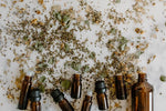 Small brown vials laying on white surface beside grains and powders